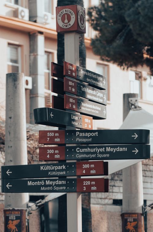 Free A close-up of a multifaceted directional sign in İzmir, Turkey, surrounded by city architecture. Stock Photo