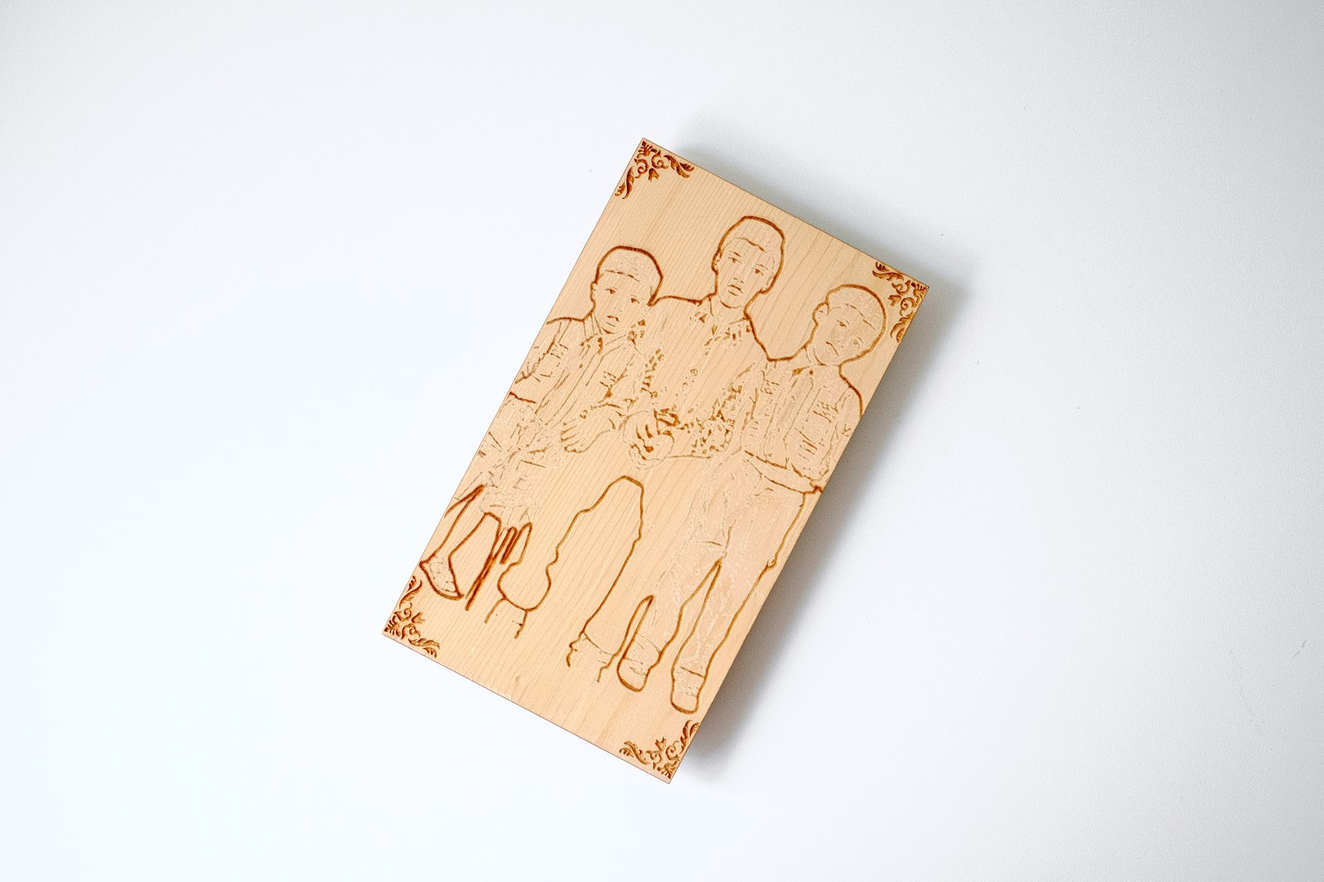 An engraved wooden plaque with a detailed family portrait on a minimalist desk.