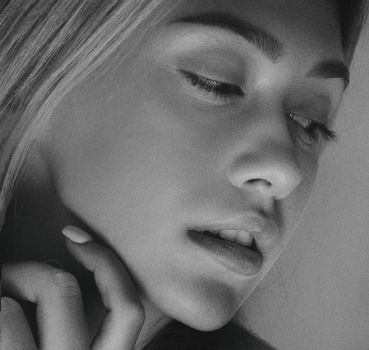 Artistic black and white close-up portrait capturing a young woman's thoughtful expression.