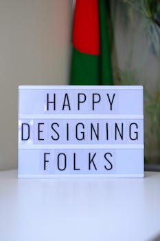 Lightbox sign displaying 'Happy Designing Folks' in an office space.