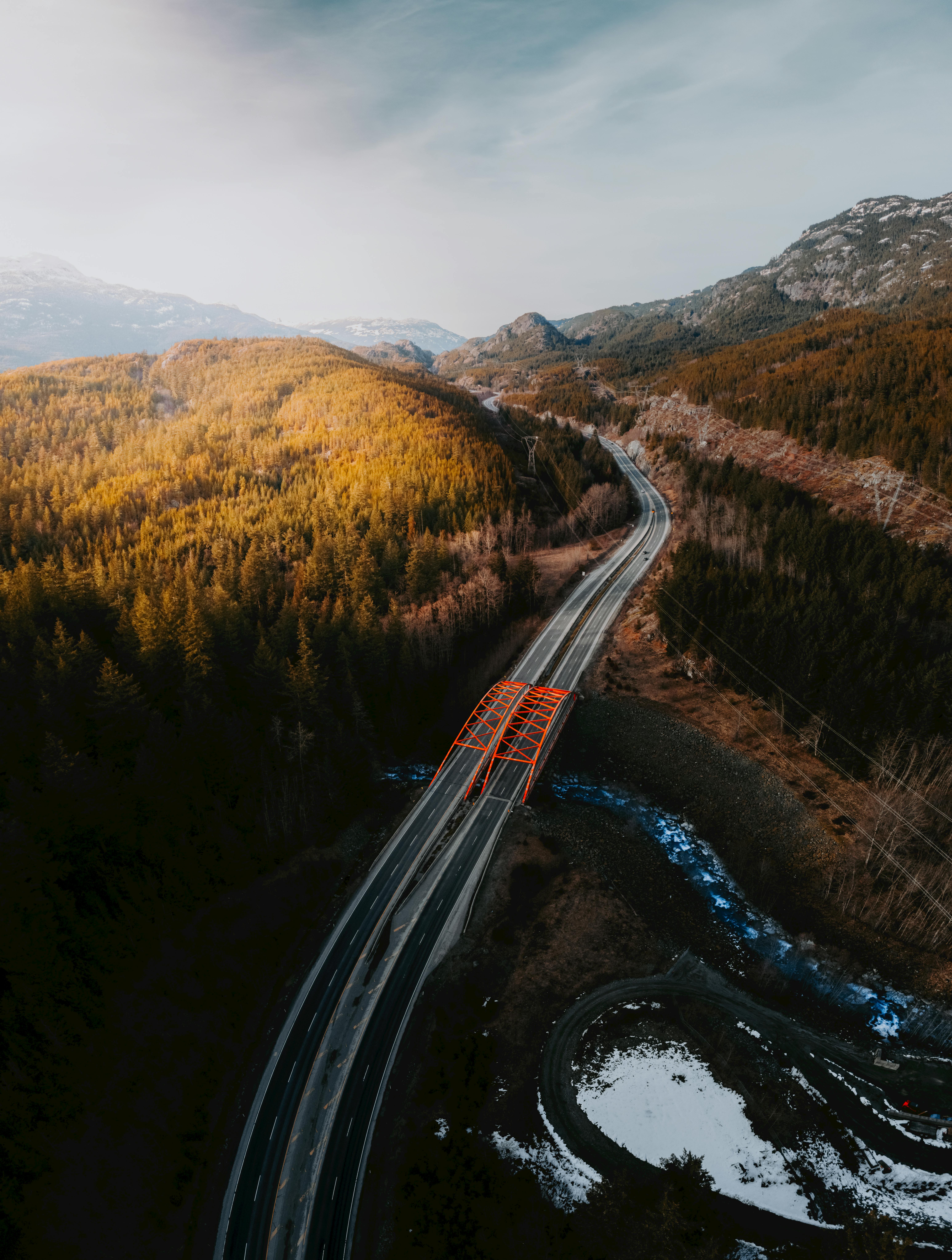Aerial shot of a scenic red bridge amidst a lush forest in Squamish, BC, Canada.