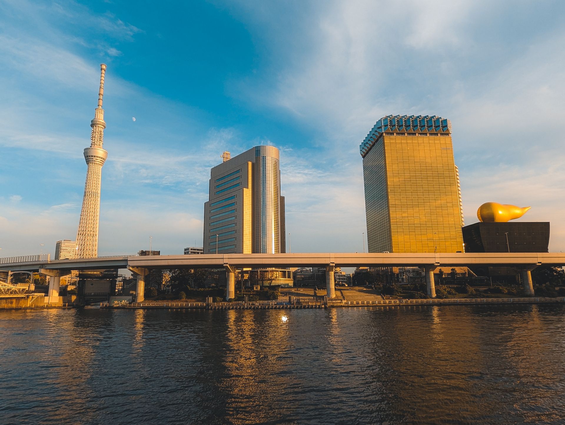 Scenic view of Tokyo's skyline featuring the Tokyo Skytree and Asahi Beer Tower during the day over water.
