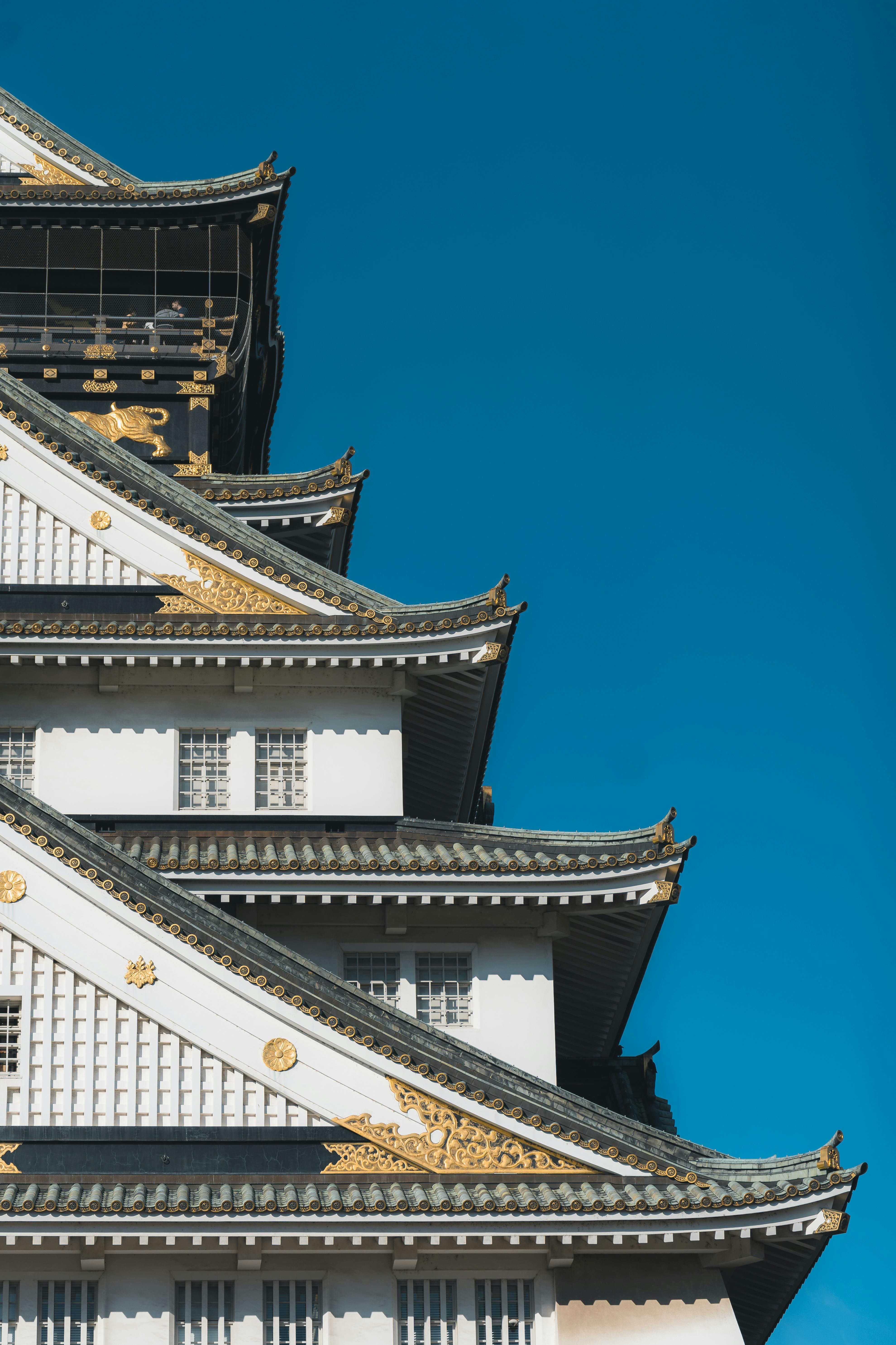 Close-up of the iconic Osaka Castle featuring traditional Japanese architecture against a vibrant blue sky.