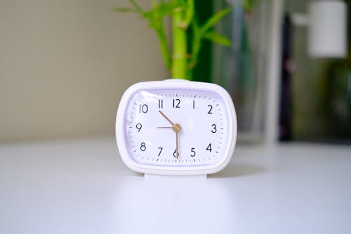 A white alarm clock sitting on a table