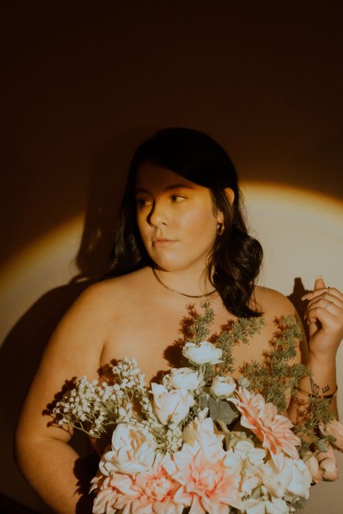 Free Artistic portrait of a woman holding a vibrant floral bouquet enhanced by moody lighting. Stock Photo