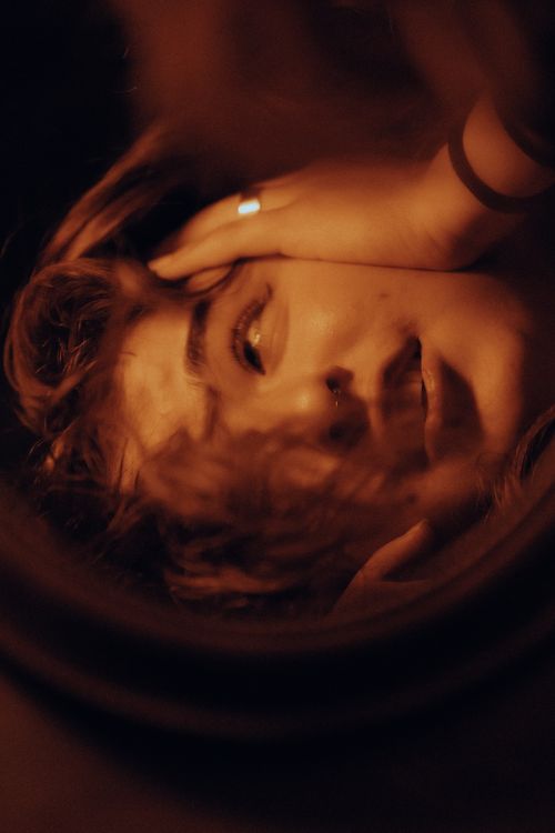 Free Close-up portrait using reflection for a creative, moody effect in warm tones. Stock Photo