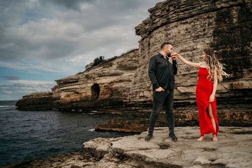 Young Couple in Elegant Clothes Dancing on the Shore next to a Cliff 