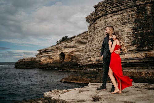 Young Couple in Elegant Clothes Standing on the Shore next to a Cliff 