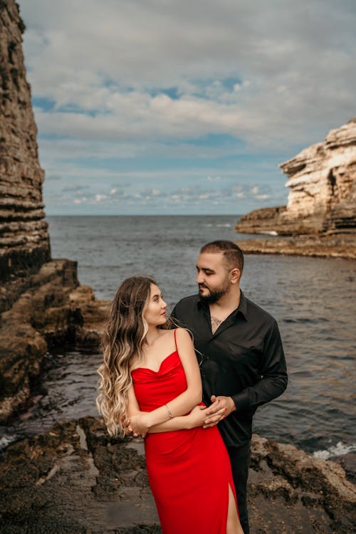 Young Couple in Elegant Clothes Standing on the Shore next to a Cliff 
