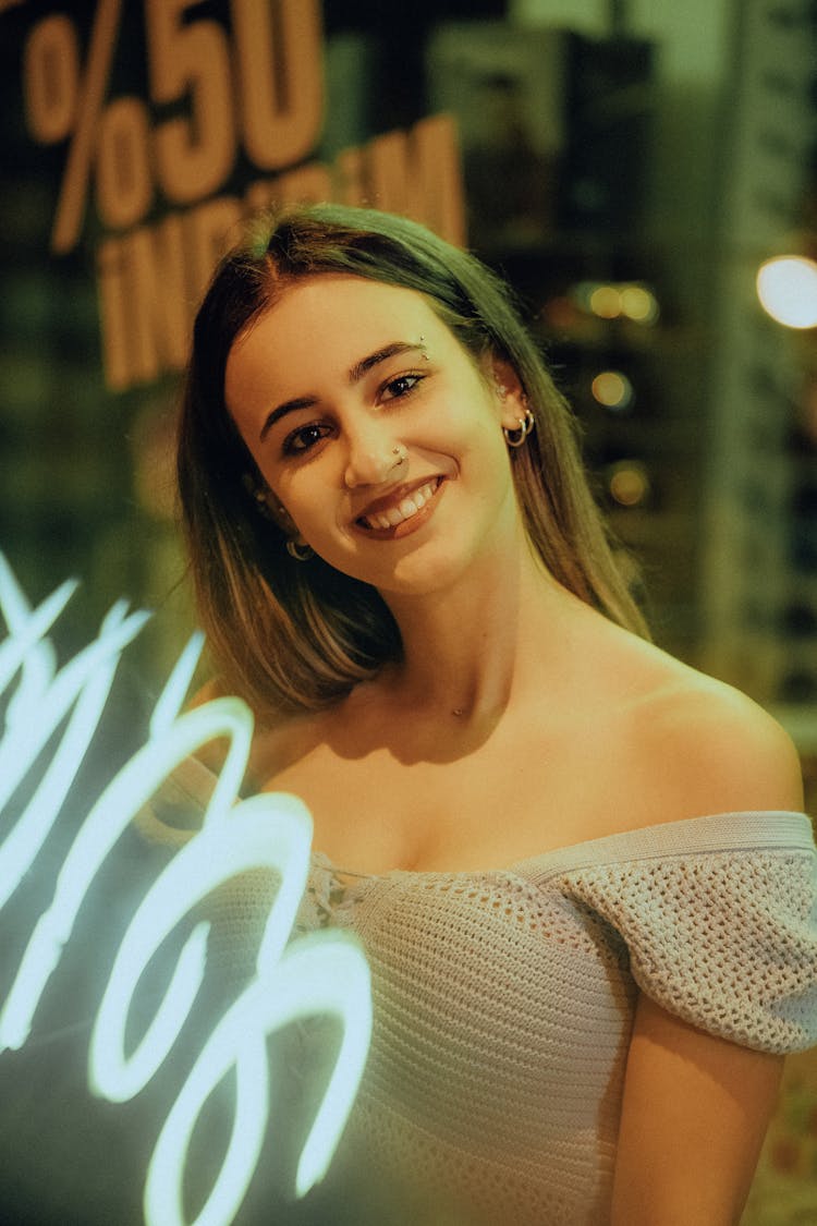 Portrait Of Smiling Woman Wearing Crotchet Top Standing By Neon Sign