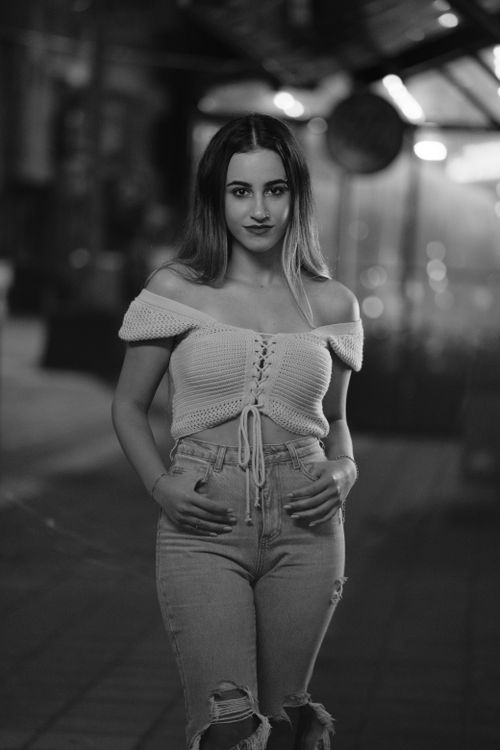 Free Black and white portrait of a woman in a crocheted top and jeans in an urban setting at night. Stock Photo