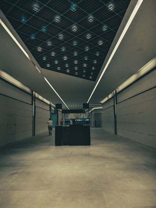 Free A lone person walking in a modern subway corridor featuring sleek architectural lines and a illuminated ceiling. Stock Photo