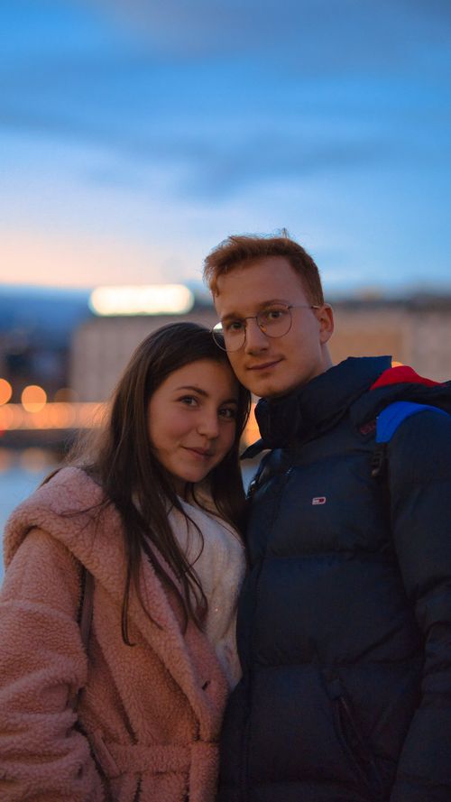 Free A fashionable couple in warm coats happily embracing during a twilight evening outdoors. Stock Photo