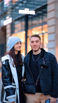 Smiling couple in stylish coats and hats posing on a city street.