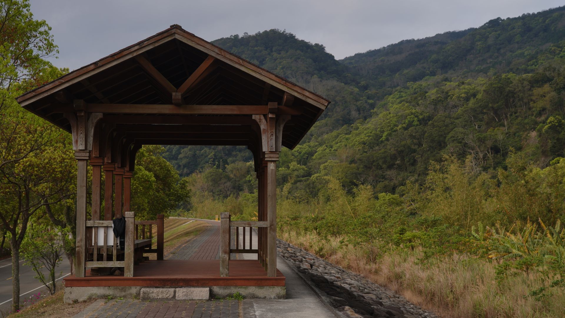 A peaceful wooden gazebo with forested mountains in the backdrop, offering a serene nature escape.