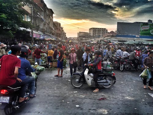 Wanita Berjaket Abu Abu Dan Merah Mengendarai Motor Putih Di Tempat Ramai