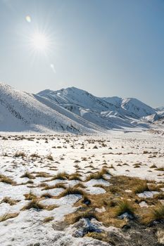 Stunning winter landscape of snow-covered mountains in Queenstown with clear skies and bright sun.