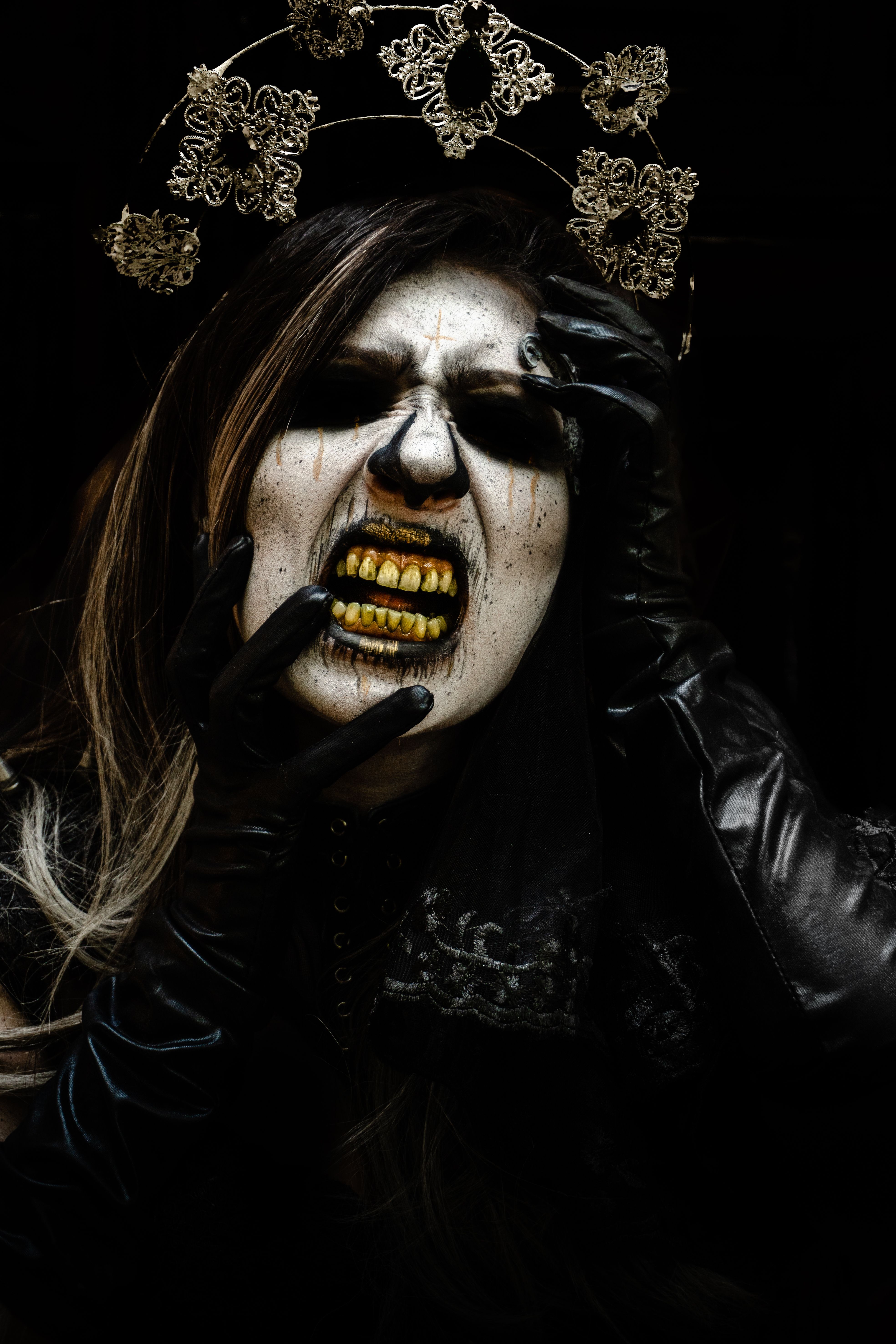 Fotomural Retrato oscuro y escalofriante de una mujer con maquillaje gótico, corona dorada y pose expresiva para Halloween.
