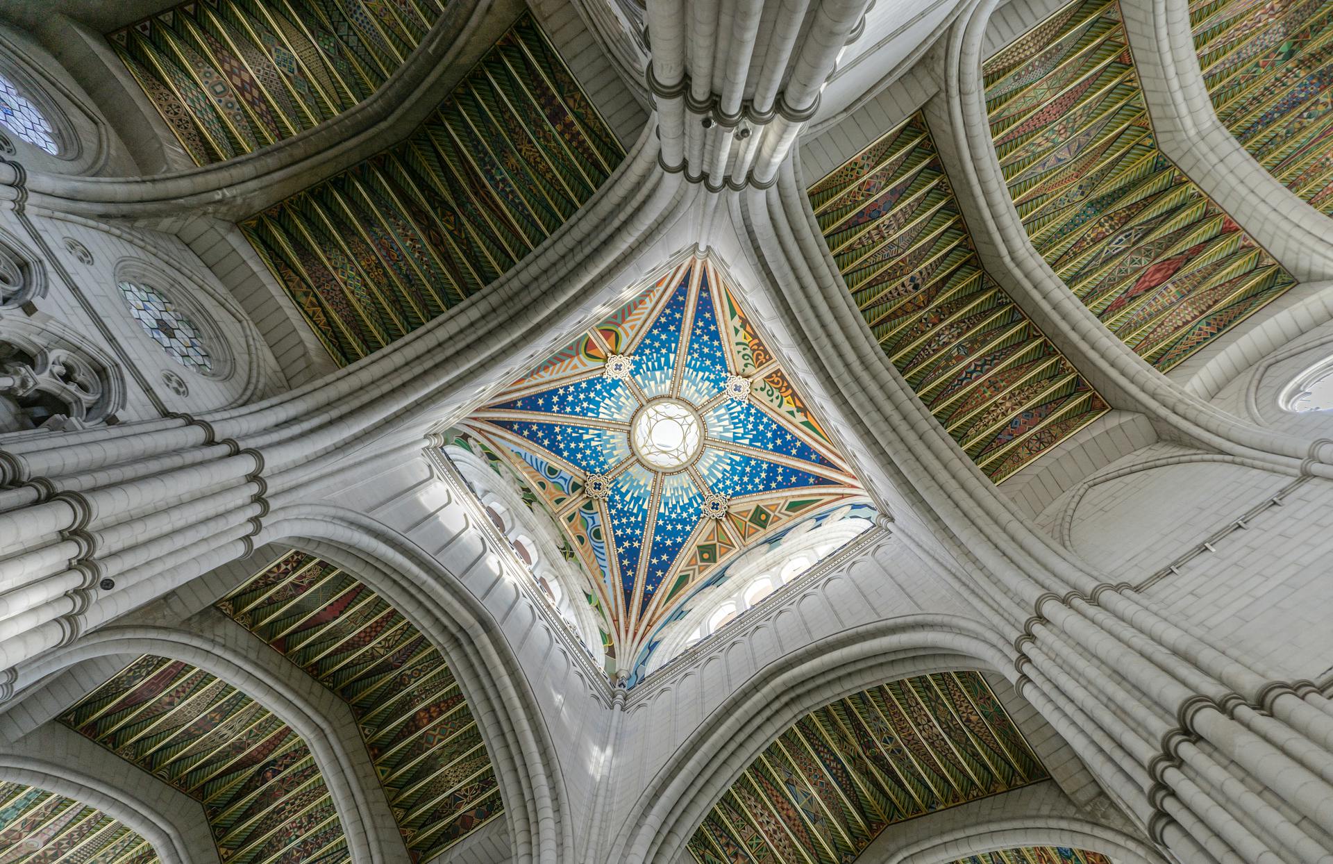 A breathtaking view of a cathedral's vaulted ceiling featuring ornate designs and vibrant stained glass.