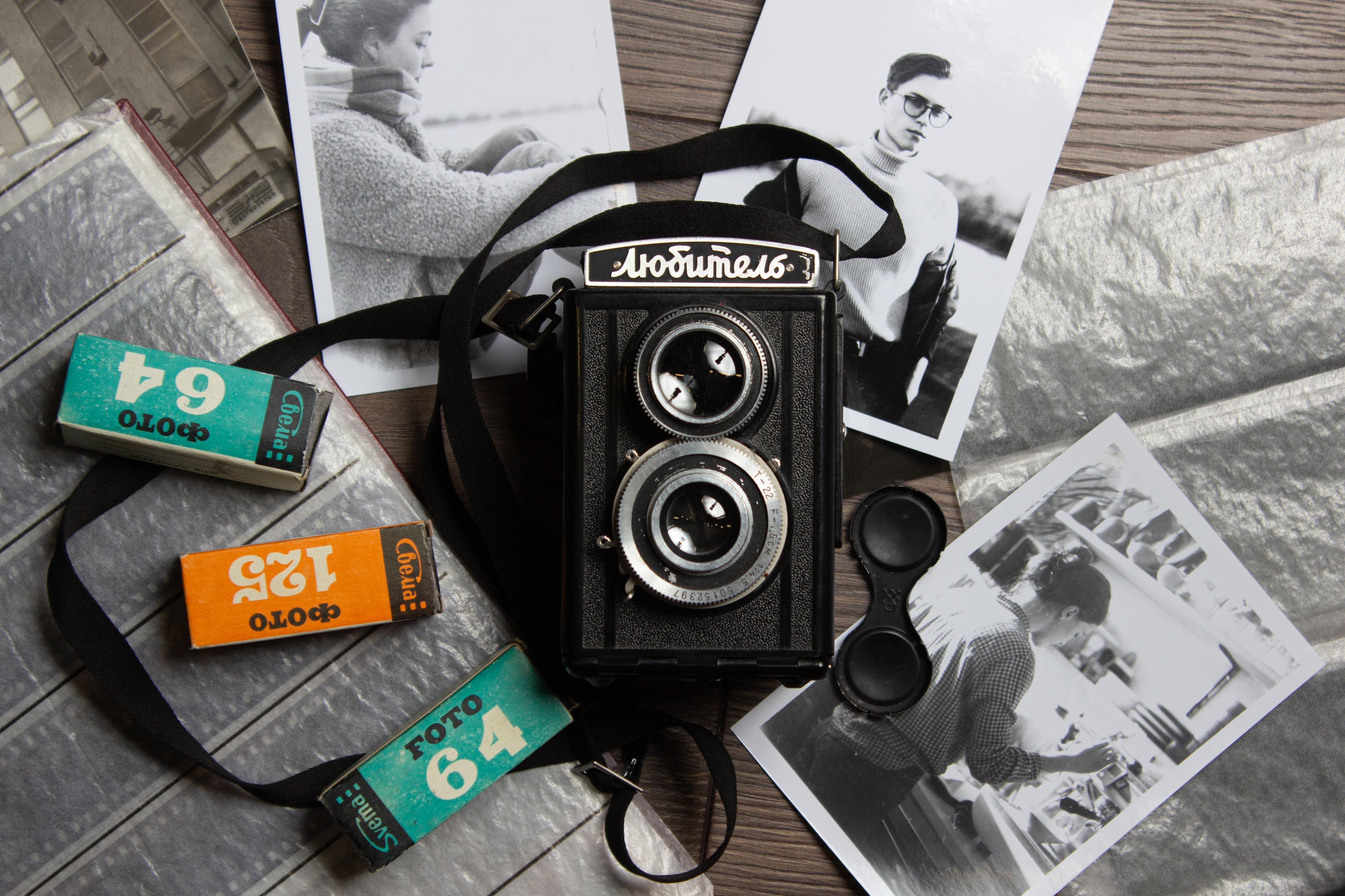 Classic Lubitel camera with film rolls and black-and-white photos in a nostalgic setup.