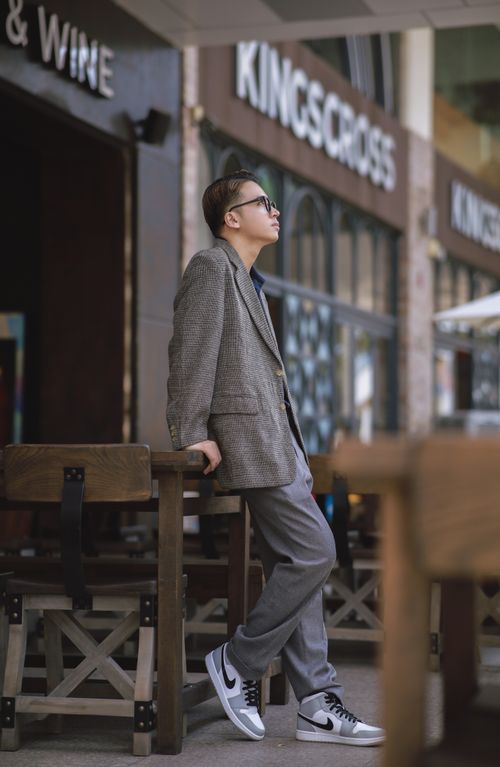 Free Fashionable man in glasses and suit leaning against table at outdoor café. Stock Photo
