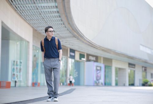 Free Fashionable man posing in city setting, wearing blue shirt and backpack. Urban lifestyle vibe. Stock Photo