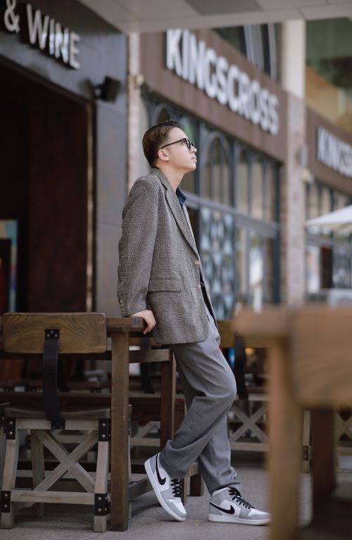 Free Fashionable man in sunglasses leans in a city café wearing a suit, capturing urban style. Stock Photo