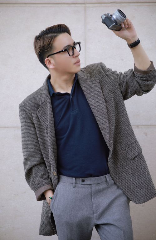 Free Stylish man in eyeglasses holding a camera, showcasing modern fashion with a blazer outfit. Stock Photo