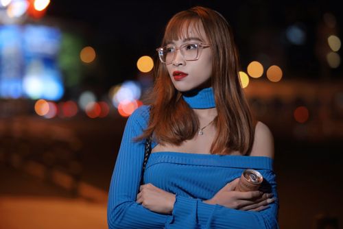 Free Portrait of a fashionable woman in eyeglasses and blue blouse posing at night with urban lights. Stock Photo
