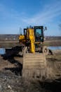 Yellow Excavator on Construction Site by Riverbank