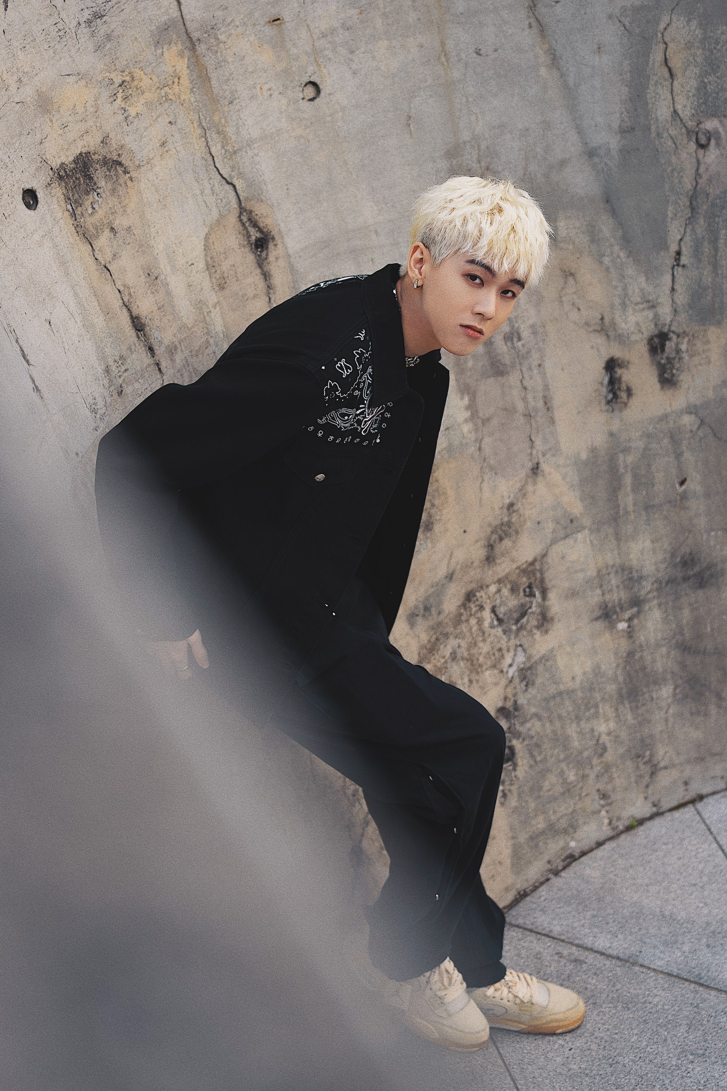 Stylish portrait of a blonde model in black attire against urban backdrop.