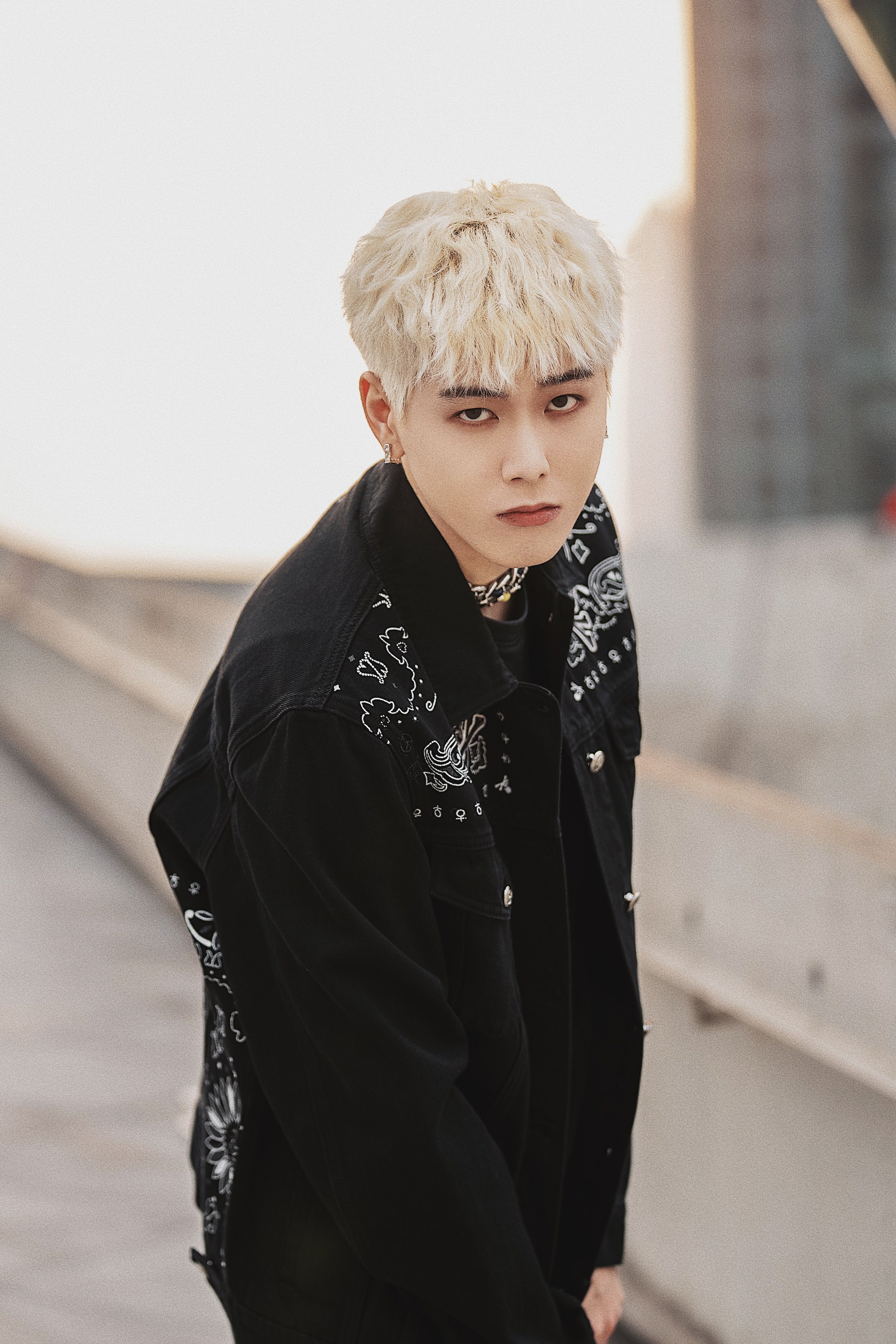 Stylish blonde model posing in a black jacket, exemplifying trendy outdoor fashion.