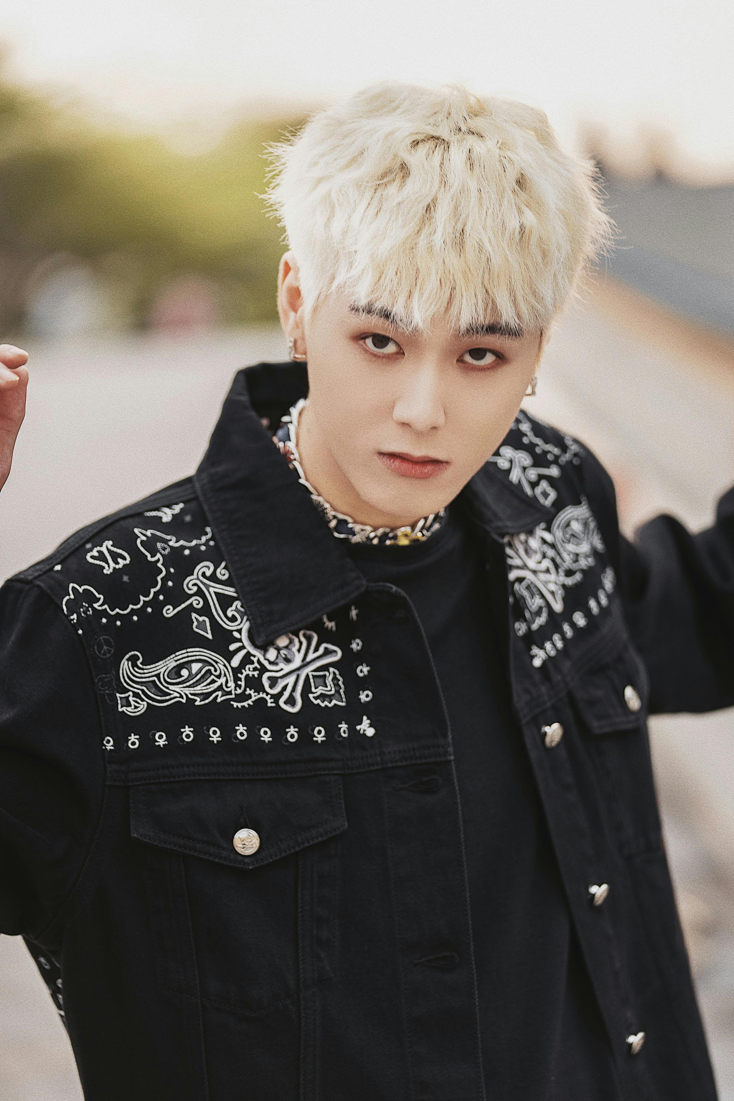 Young adult in a stylish black jacket outdoors, showcasing modern fashion trends.