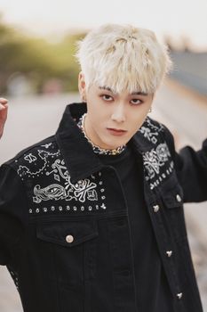 Young adult in a stylish black jacket outdoors, showcasing modern fashion trends.