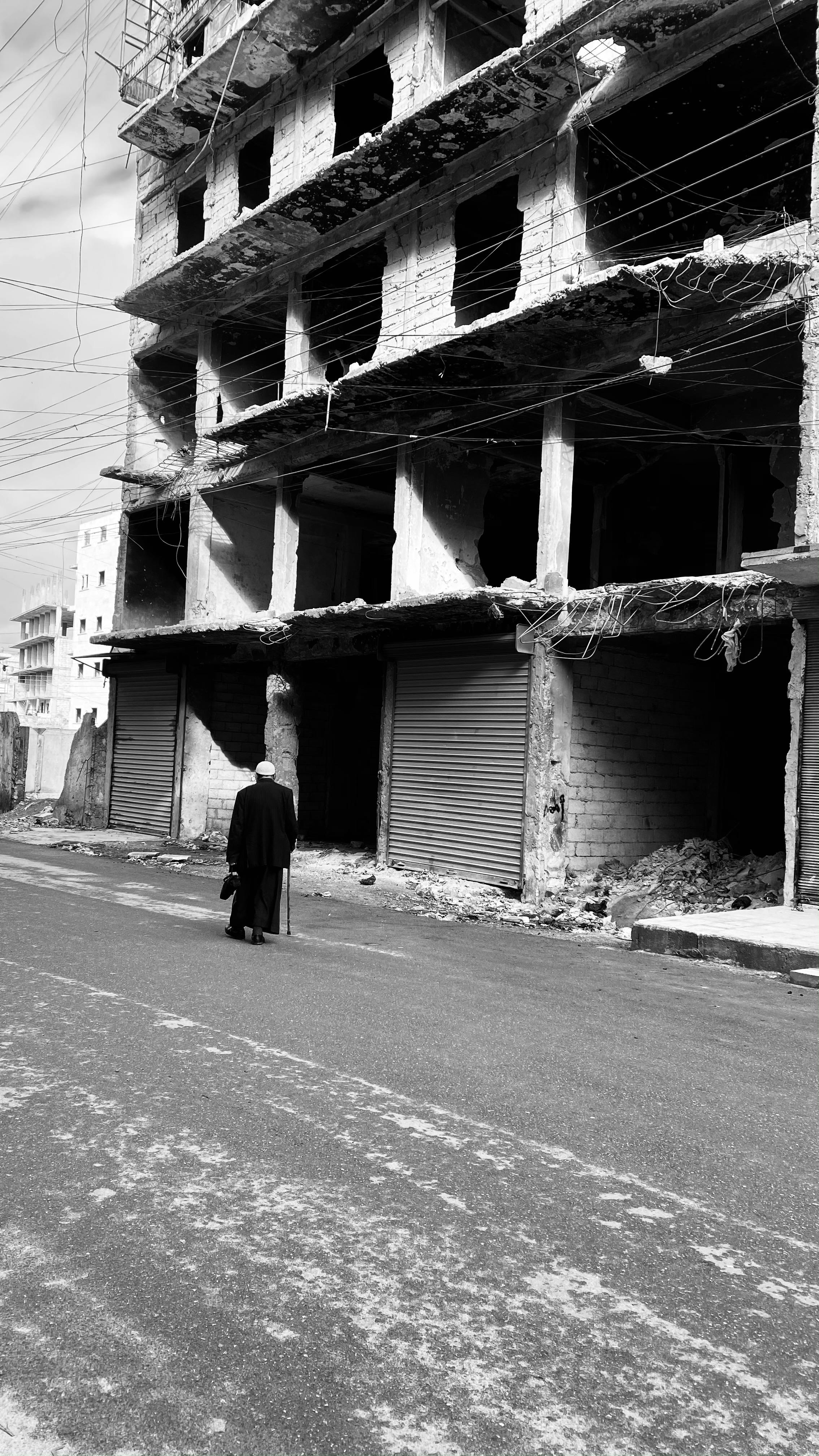 A lone person walks past damaged buildings in war-torn Aleppo, Syria.