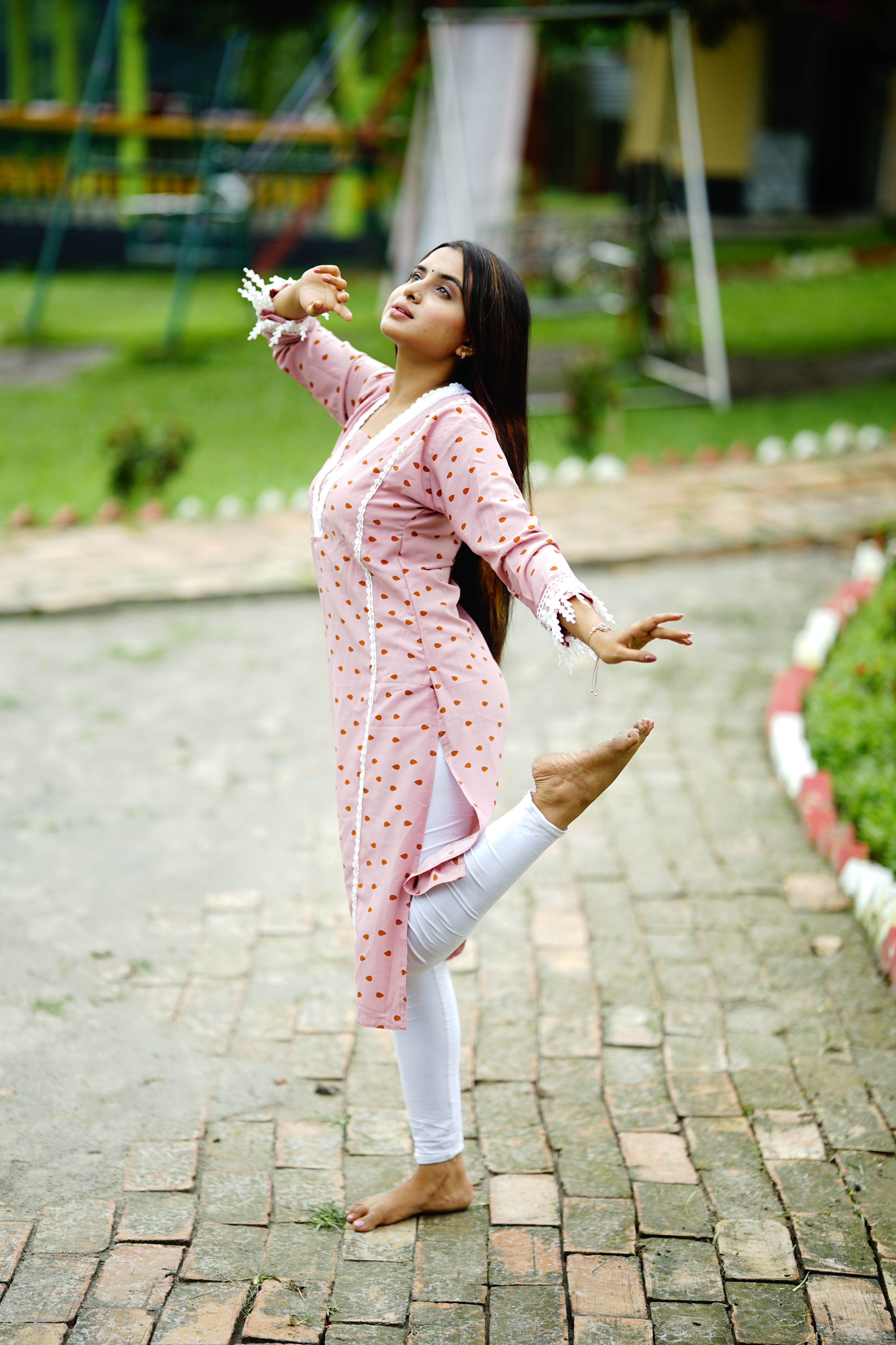 Carefree woman in a stylish dress enjoying a moment of freedom in a park setting.