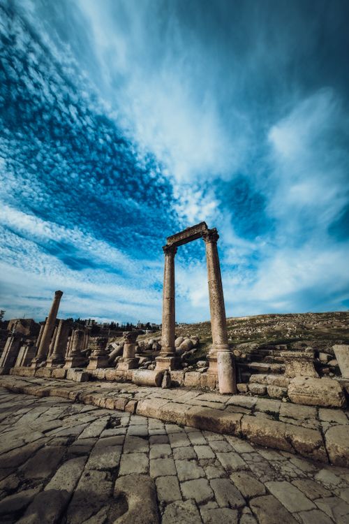 Free Scenic view of Roman ruins in Jordan with a majestic cloud-filled sky, showcasing ancient architecture. Stock Photo
