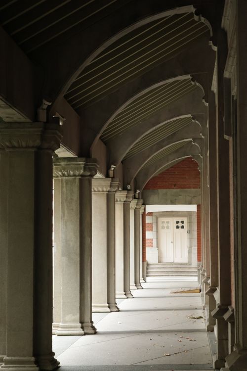 Free A serene corridor featuring elegant columns and arches leading to a distant door. Stock Photo