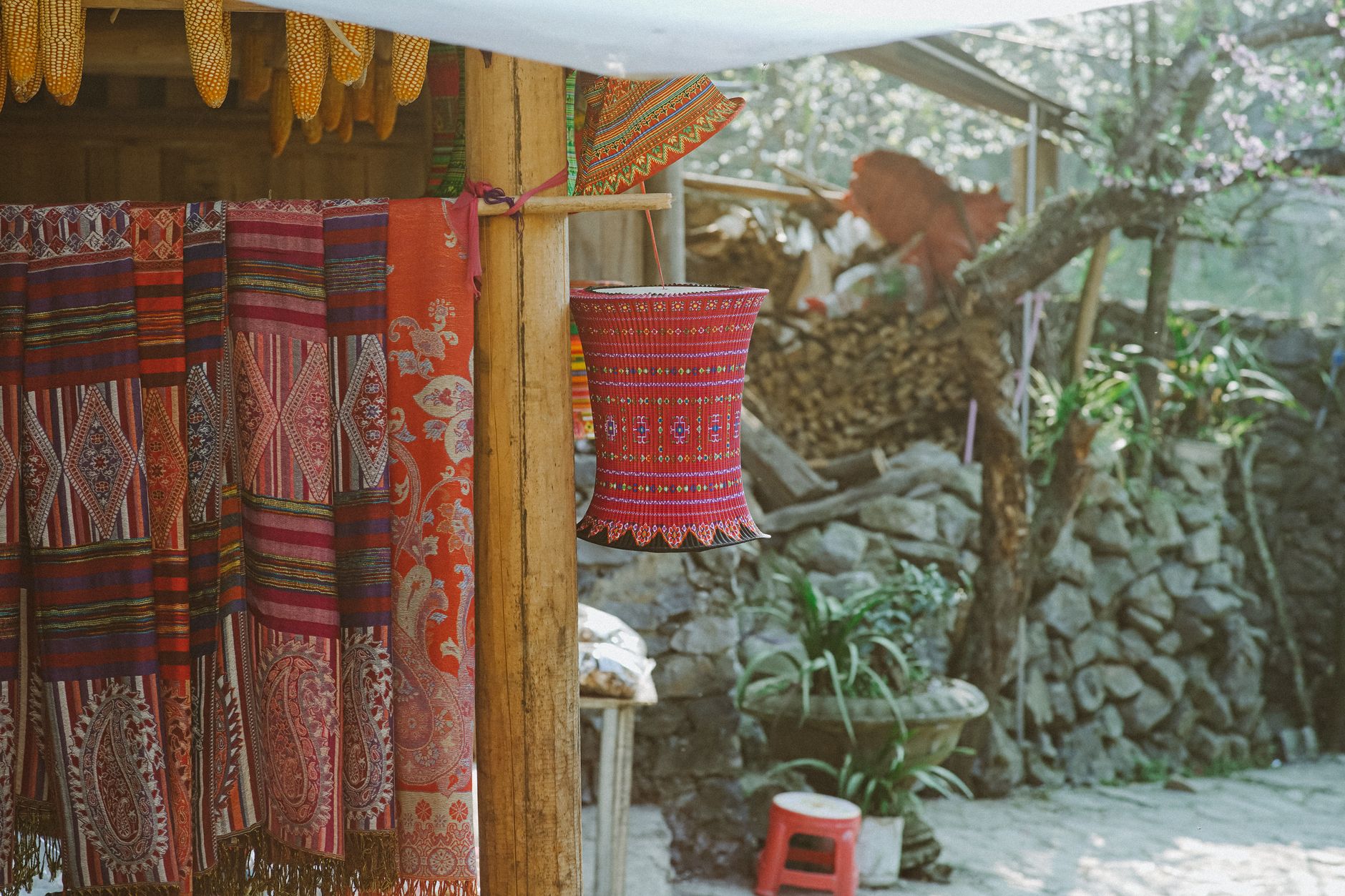 Leuchtend bunte traditionelle vietnamesische Textilien im Freien vor rustikalem Hintergrund.
