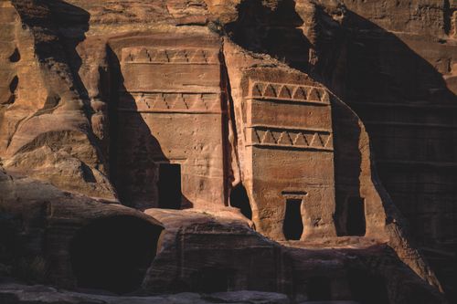 Free Detailed view of sunlit ancient rock carvings on a stone cliff, showcasing historical architectural artistry. Stock Photo
