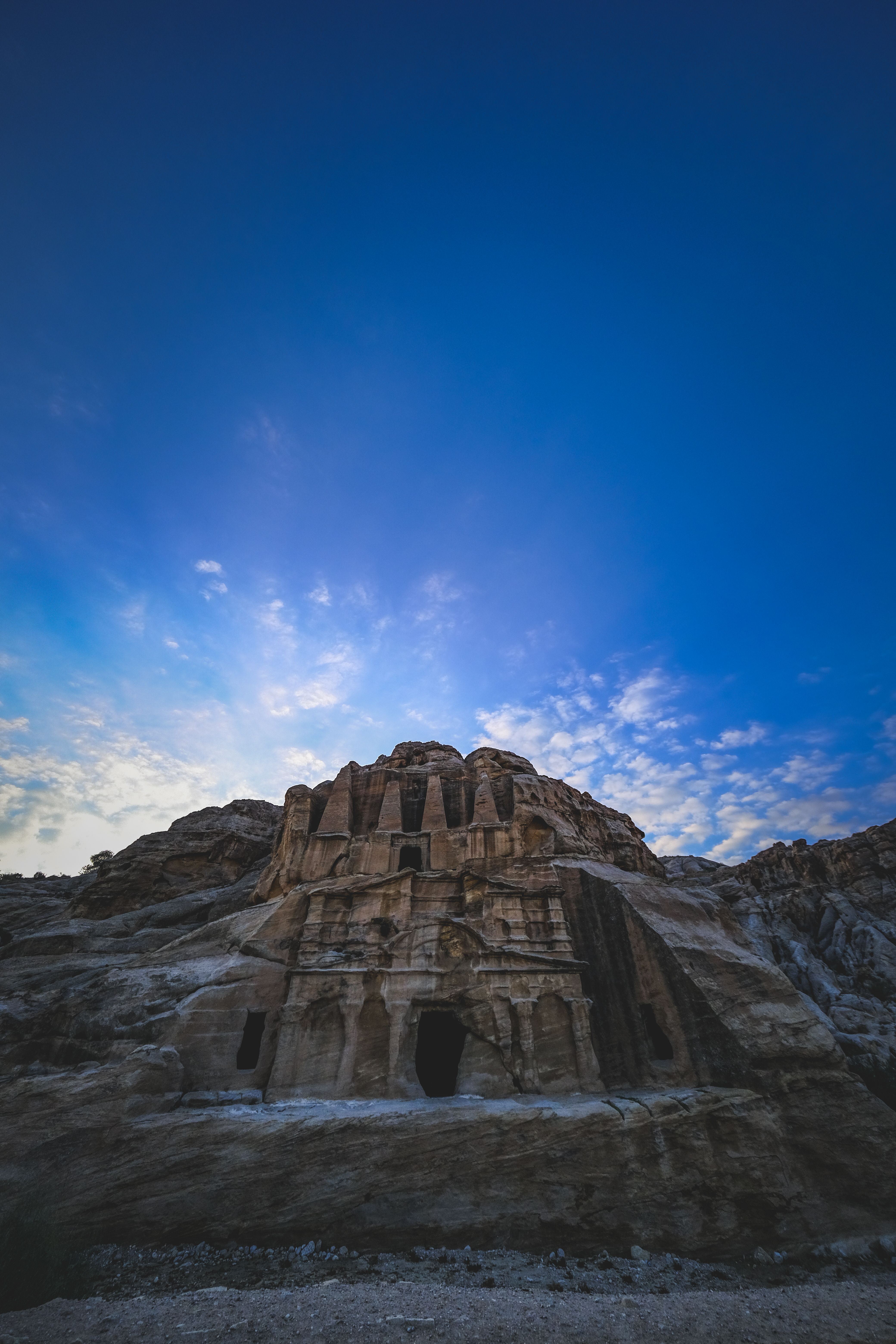 Stunning view of Petra's ancient stone tombs beneath a vibrant desert sky at dusk.
