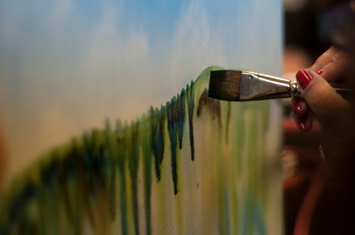 Woman With Red Nails Painting Green Stripe on Canvas