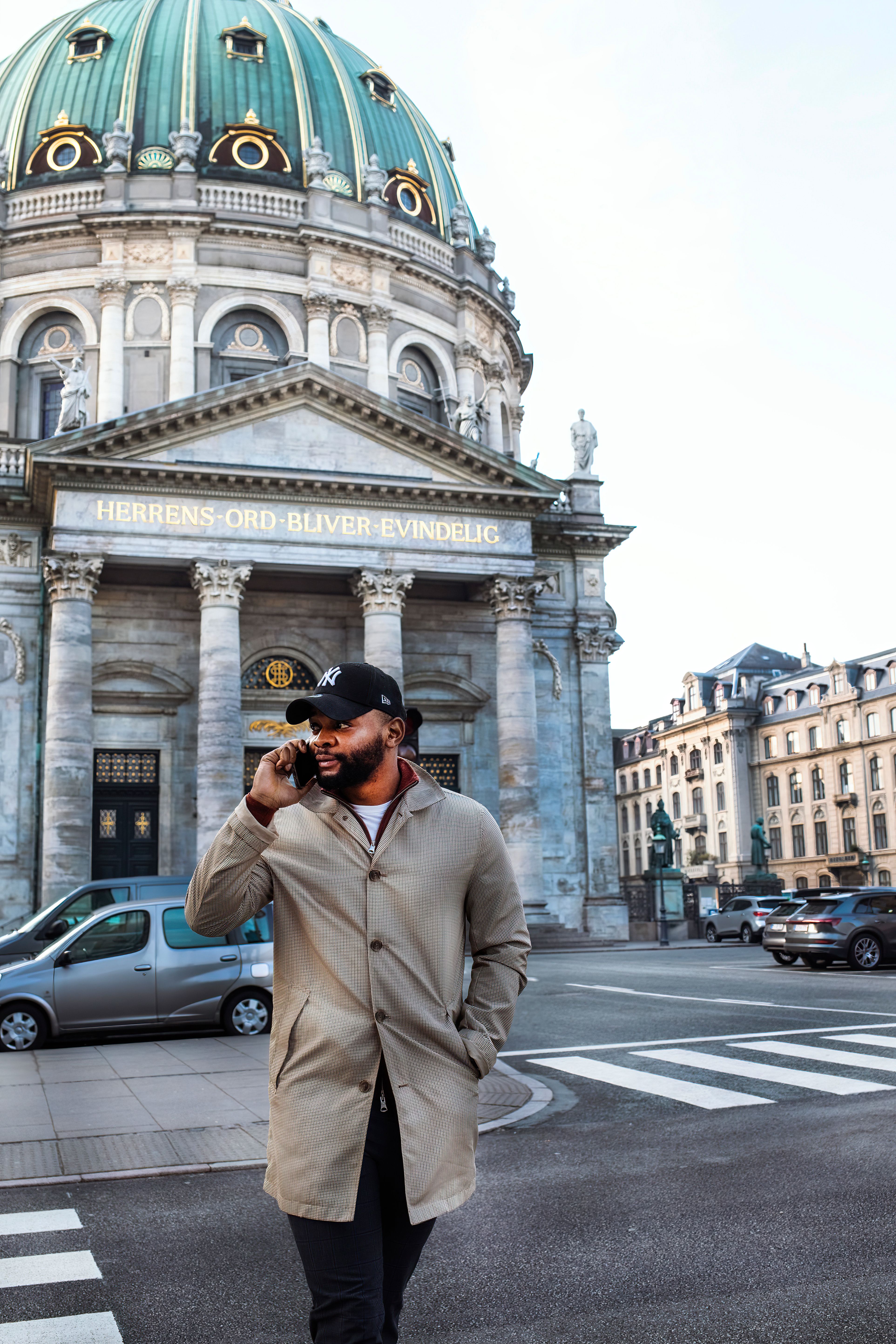 A man is talking on his phone while walking in front of Frederik's Church in Copenhagen.