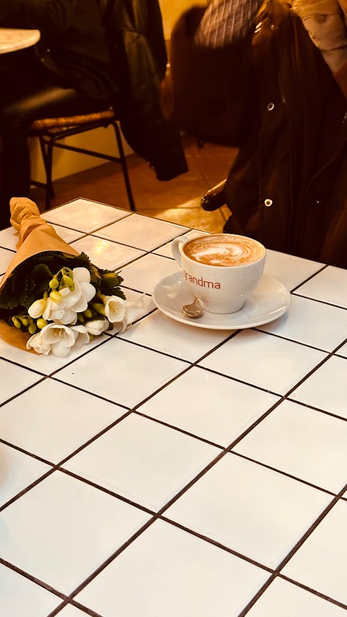 Free Bouquet of Flowers and a Cup of Coffee on a Restaurant Table  Stock Photo