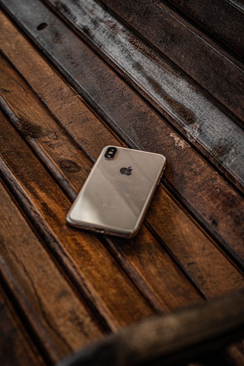 Free Close-up of a smartphone resting on a rustic wooden bench, symbolizing technology in a natural setting. Stock Photo