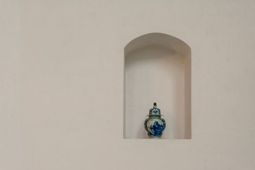 Elegant blue porcelain vase displayed on a minimalist white wall shelf with ample copy space.