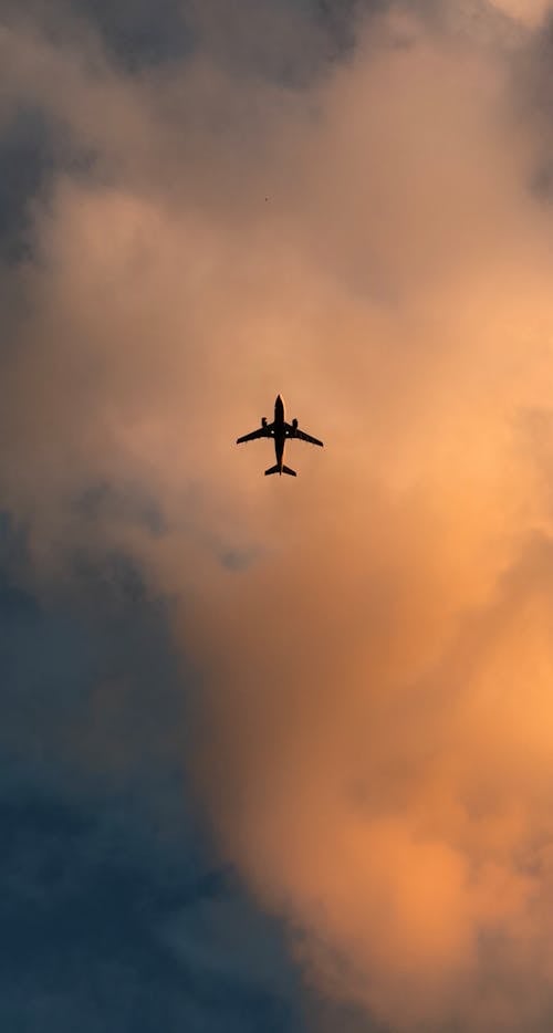 Airplane under Clouds at Sunset