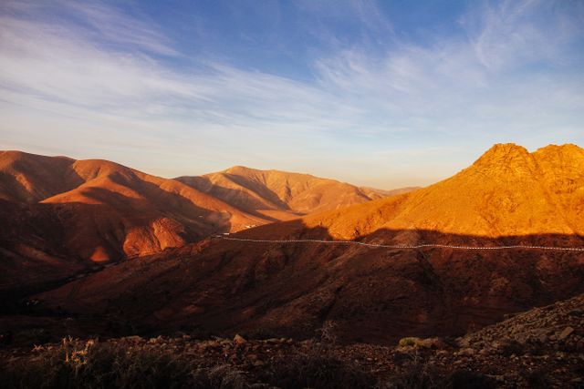 Empty road running through arid hills at dusk — photo by Francesco Ungaro on Pexels