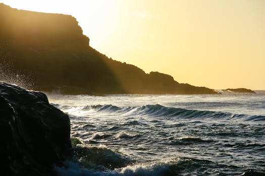 日落时分，海浪拍打着岩石海岸，温暖的阳光洒在现场