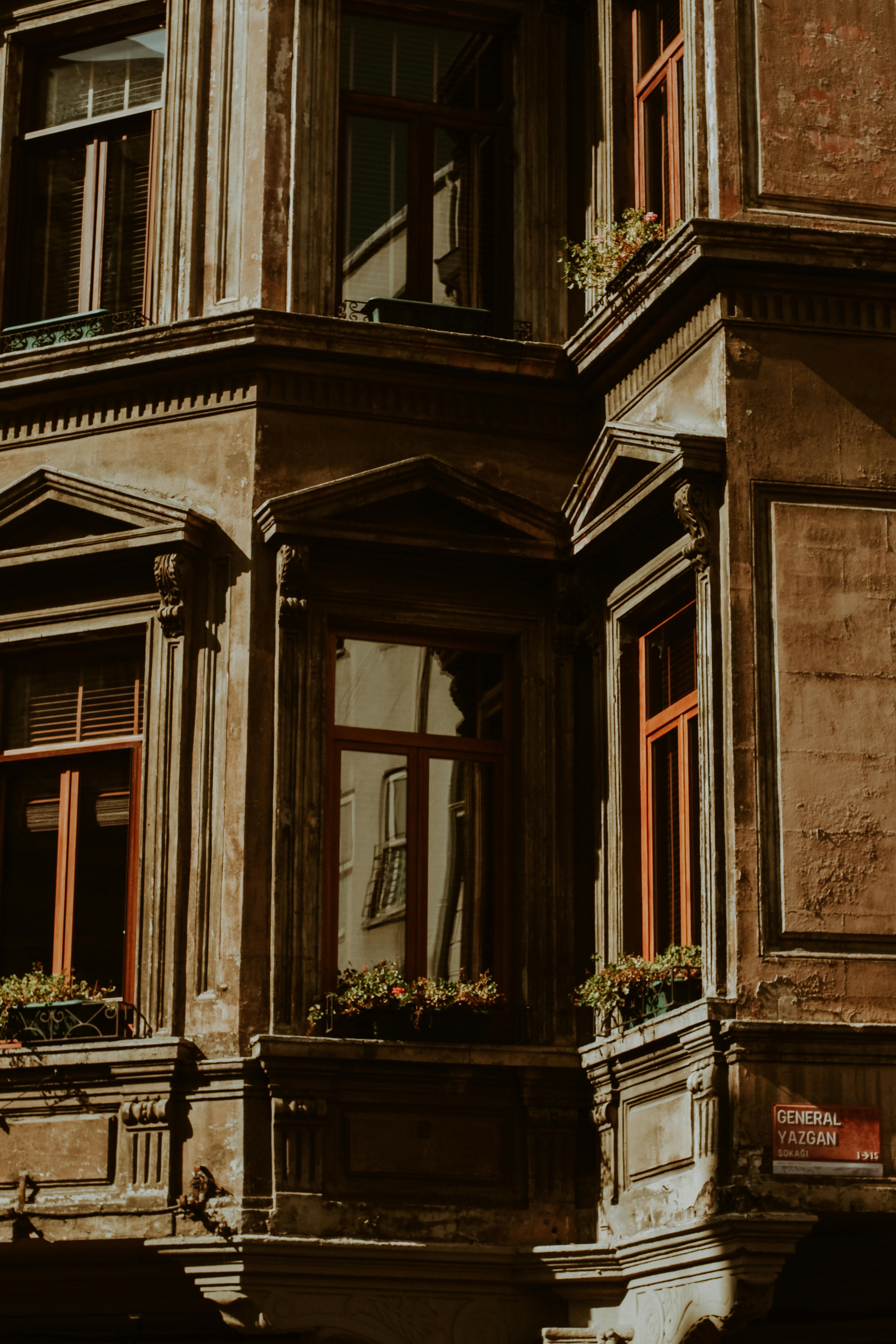 Free Close-up of a sunlit vintage building facade with intricate details and windows. Stock Photo